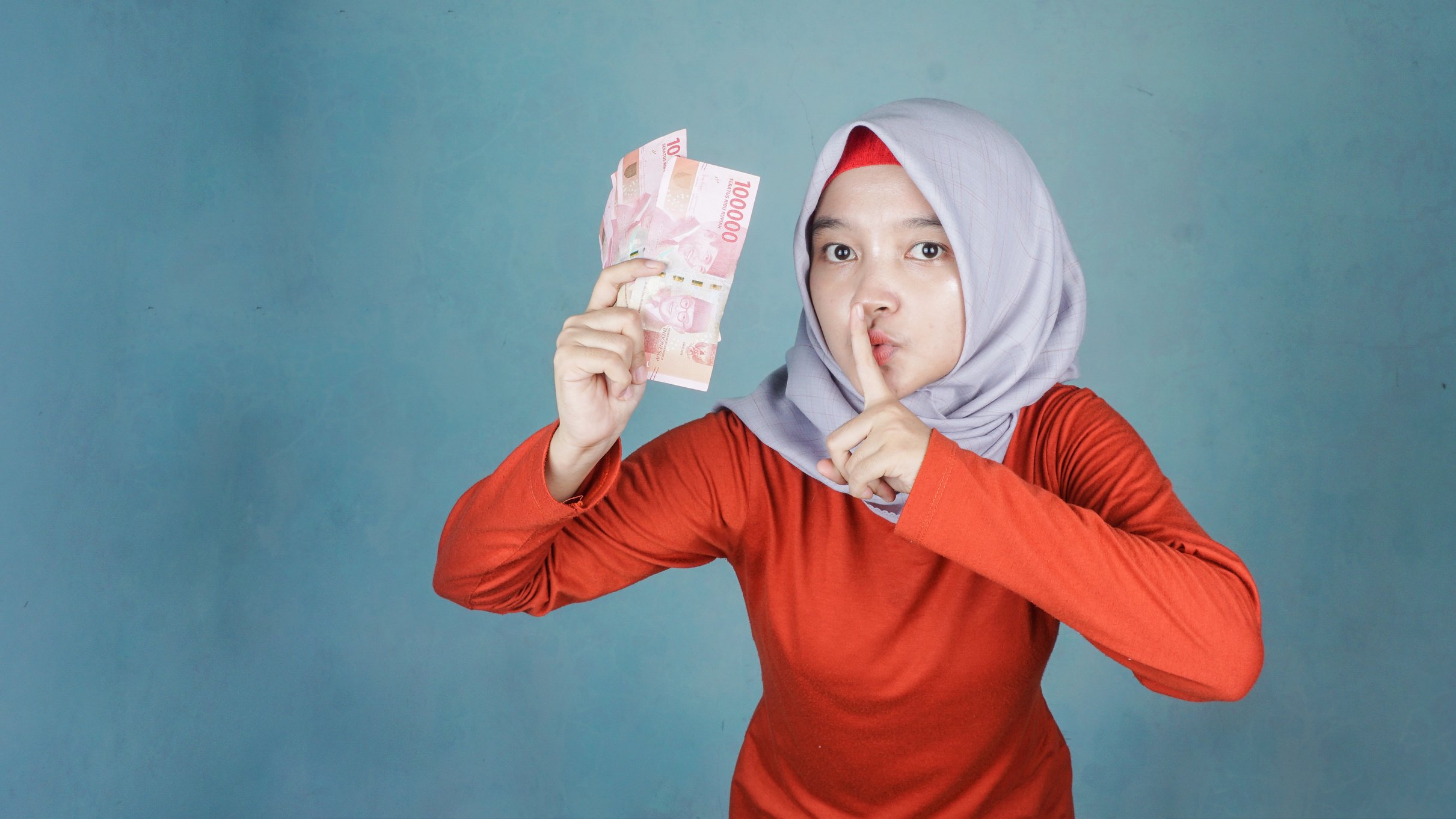 Beautiful muslim woman holding indonesia rupiah money asking to